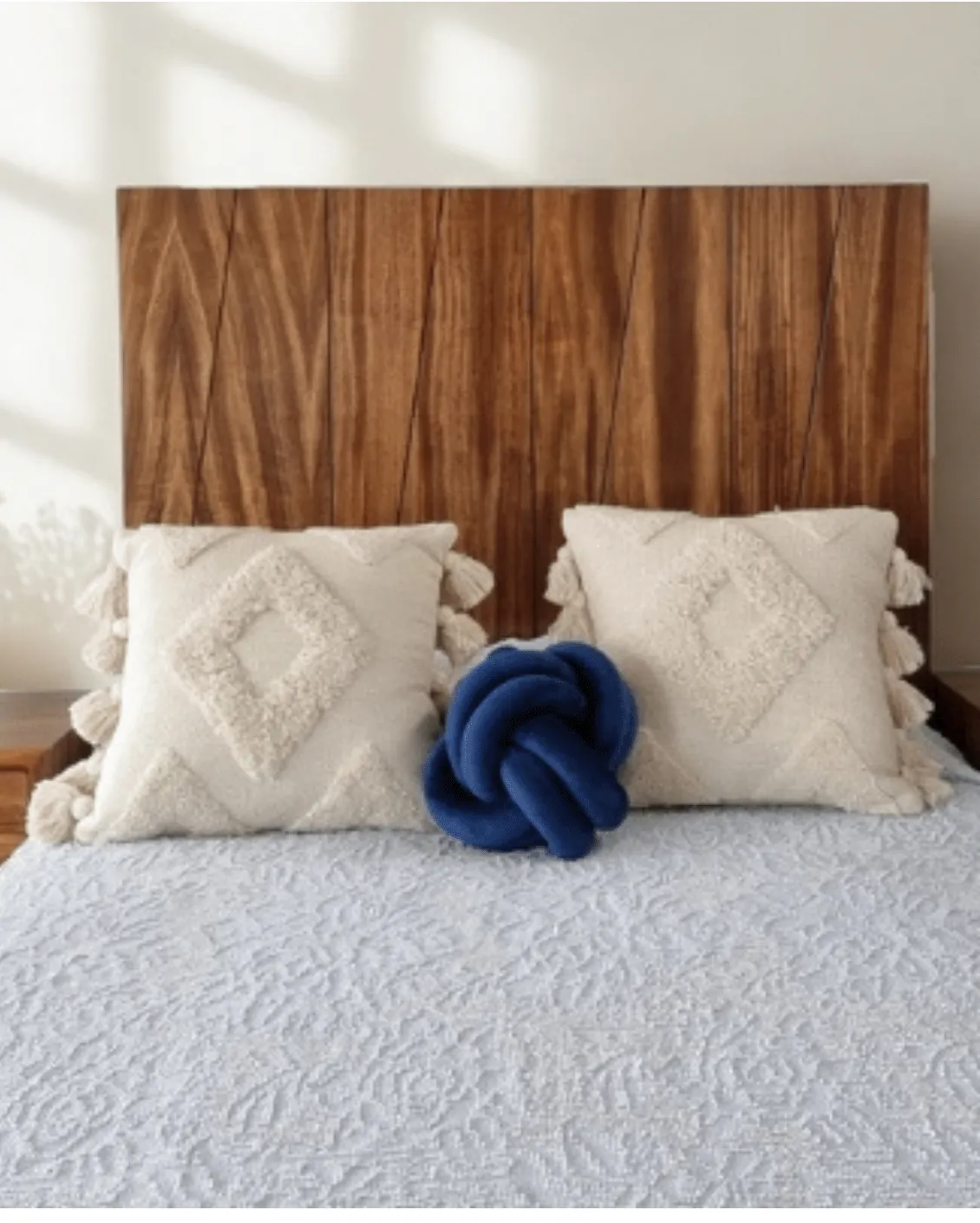 Cabecera de madera con veta diagonal, cojines texturizados y cojin nudo azul