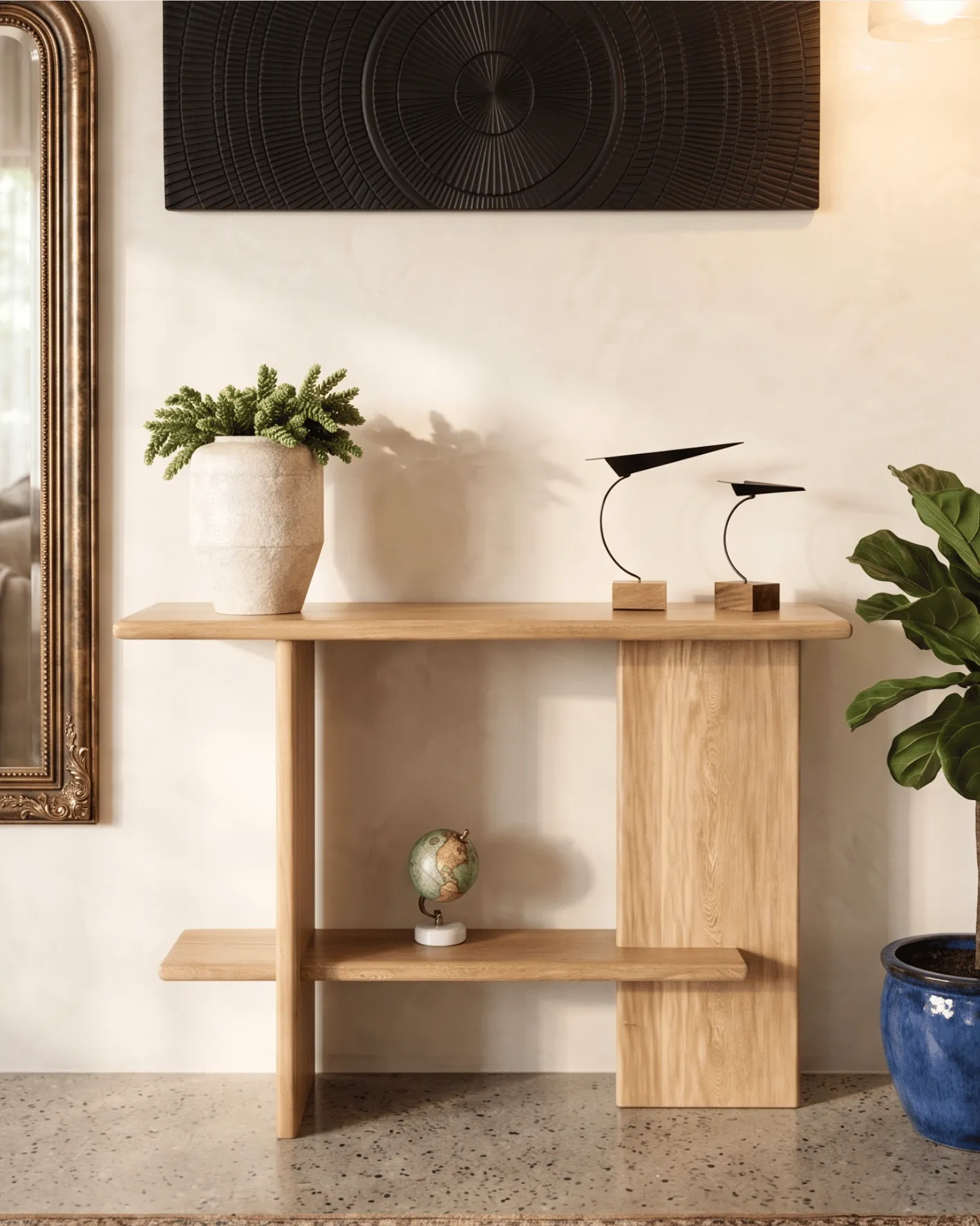 Consola de madera clara con planta, esculturas de aves y maceta azul junto a espejo
